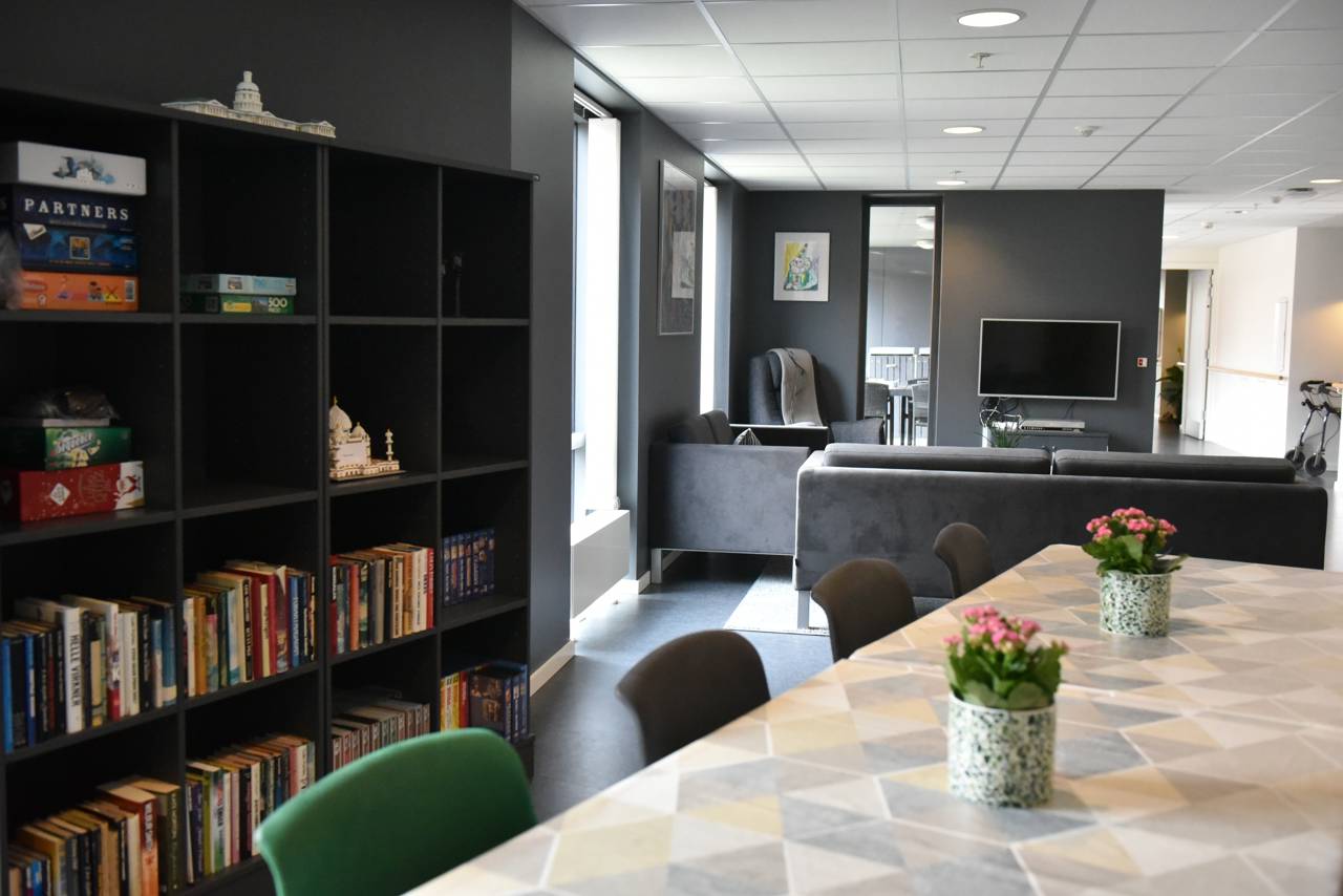 Opholdsrum med spisepladser, bogreol og tv-stue