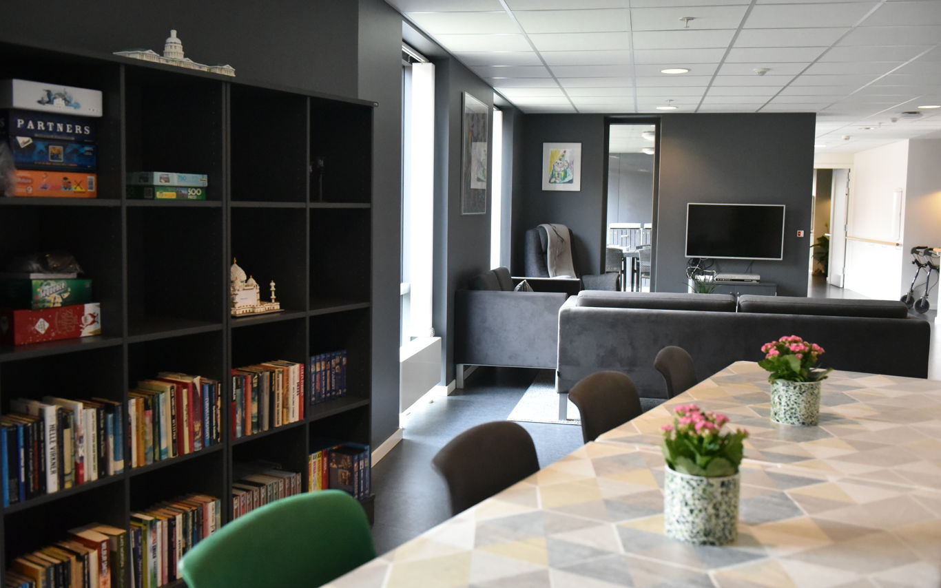 Opholdsrum med spisepladser, bogreol og tv-stue