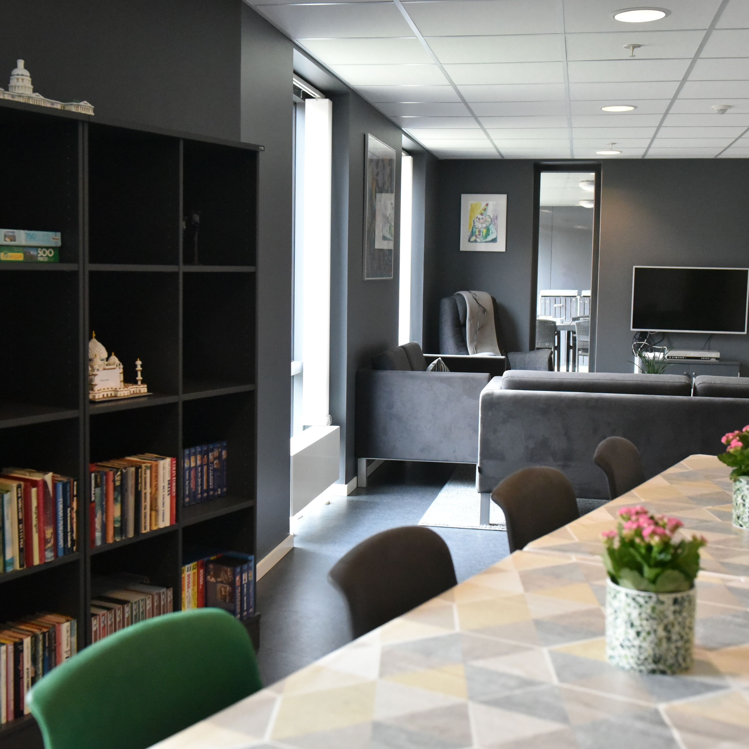 Opholdsrum med spisepladser, bogreol og tv-stue